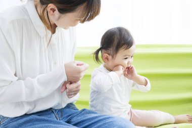 Evdeki oturma odasında genç annesiyle oynayan tatlı bir Japon kızı.