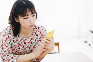 Evde akıllı telefon kullanan güzel bir Asyalı kadın.