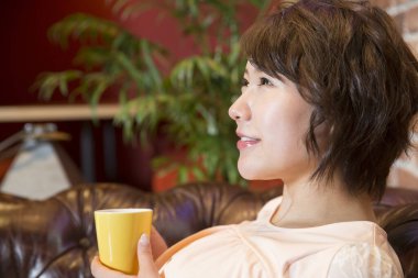 Genç Asyalı kız kafede kahve içiyor.