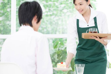 Garson müşteriye kek ikram ediyor.