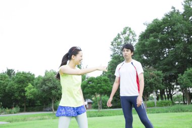 Sportif genç Asyalı çift parkta koşmadan önce geriniyor.