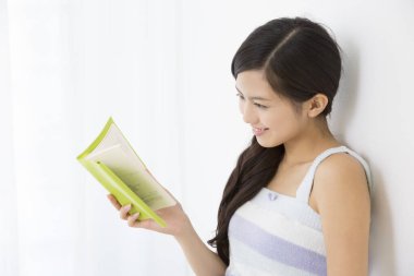 Evde kitap okuyan genç bir kadın.