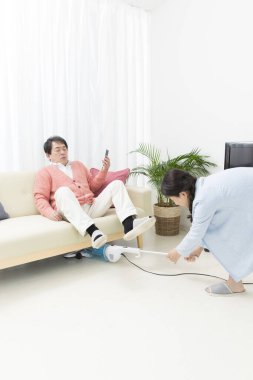 Akıllı telefonu olan bir adam ve odada elektrikli süpürgesi olan bir kadın. 