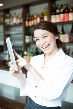 Restoranda tablet kullanan neşeli Asyalı garsonun portresi