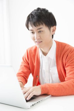 Genç Japon adam dizüstü bilgisayarla çalışıyor.