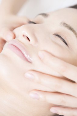 Genç ve güzel Japon kadın spa merkezinde yüz masajından zevk alıyor..