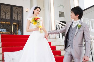 Merdivenlerde poz veren mutlu Asyalı gelin ve damadın portresi.