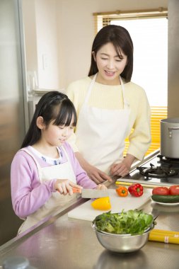 Genç anne ve kız mutfakta taze salata hazırlıyorlar. 