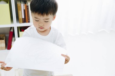 Küçük çocuk odada çizim yapıyor.