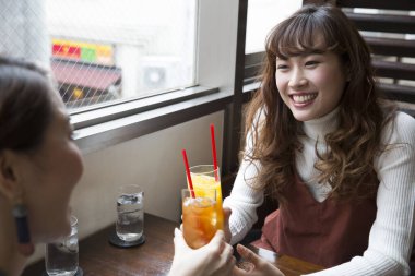 Kahvede meyve suyu içen gülümseyen Asyalı kadınlar