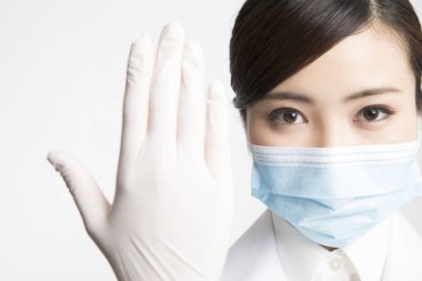 Beyaz arka planda koruyucu maskeli ve eldivenli bir doktor.