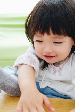 Gülen kız ahşap masada oynuyor