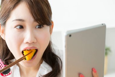 Çekici bir kadının portresi evde suşi ve çubuk yiyor.