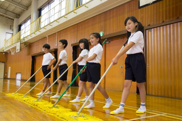group of children in a uniform cleaning sport gym in school