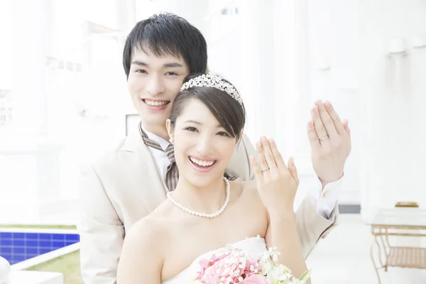 カメラで結婚指輪と笑顔を示す美しい若い結婚式のカップル — ストック写真