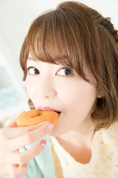 アジアの女性はドーナツを食べる — ストック写真