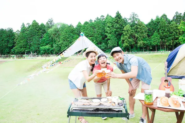 happy Japanese friends enjoying barbecue at nature