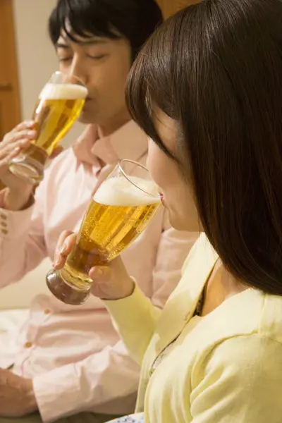 young asian couple drinking beer at home at living room