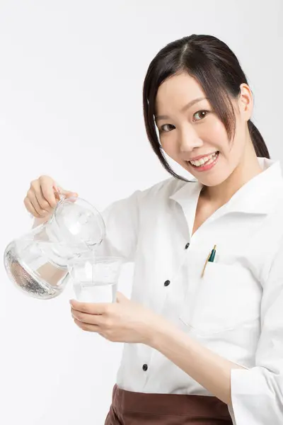 Wesoła Azjatycka Kelnerka Wlewa Wodę Dzbanka Szklanki — Zdjęcie stockowe