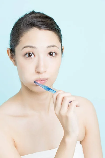 青の背景に歯を磨く若い女性 — ストック写真