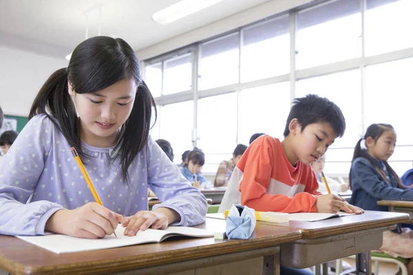 Japon ilkokul öğrencileri sınıfta yazıyor. eğitim kavramı