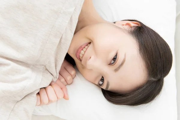 asian woman smiling in bed
