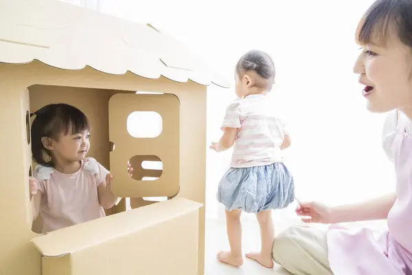 Stock image asian mother and little children playing with toy paper house