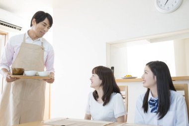 smiling asian waiter serving dish  