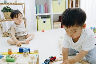 Çocuklar parlak odada tahta oyuncaklarla oynuyorlar.