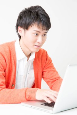 Genç Japon adam dizüstü bilgisayarla çalışıyor.