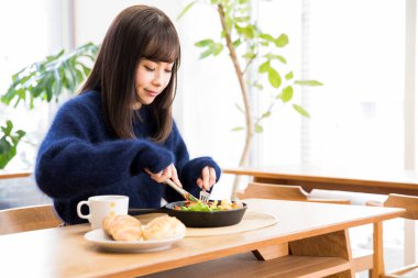 Güzel genç bir kadın Japon restoranında öğle yemeği yiyor.