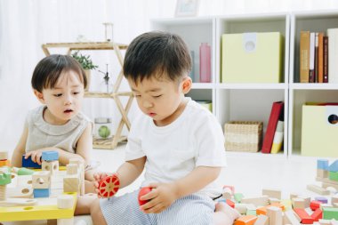 Asyalı küçük oğlan ve kız oyuncaklar ve dizüstü bilgisayarla oynuyorlar. 