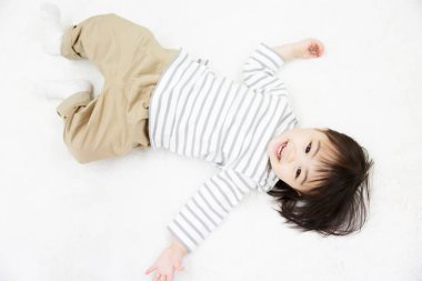 Sevimli erkek bebek beyaz yatakta yatıyor..