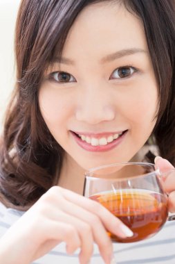 Genç Japon kadın evdeki cam bardaktan çay içiyor.