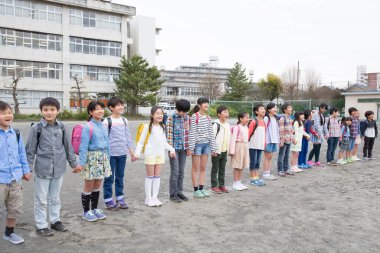 Okul bahçesinde el ele tutuşan bir grup Japon çocuk. 