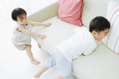 Kanepede oynayan iki genç çocuk.