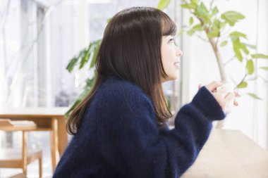 Kafede kahve içen genç Asyalı kadın.