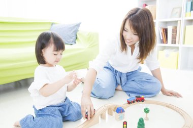 Asyalı anne ve kızı tahta oyuncaklarla oynuyorlar.