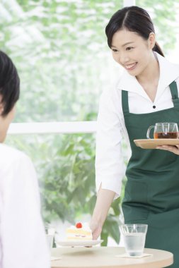 Ziyaretçilere yemek servisi yapan Asyalı garson. 