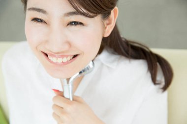 Asyalı kadın yüz gerdirme masajı için tekerlekli sandalye kullanıyor.