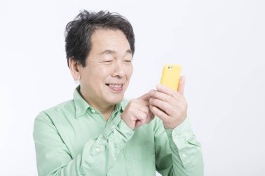 Stüdyoda duran akıllı telefonlu kıdemli Asyalı adam..