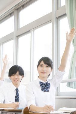 Asyalı öğrenciler sıralarda çalışıyor.