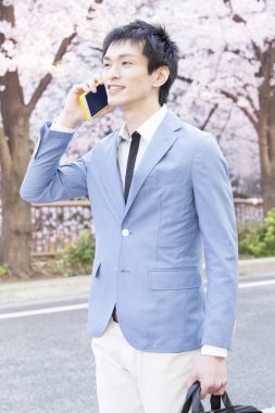 Parkta akıllı telefonu olan genç bir iş adamının portresi. 