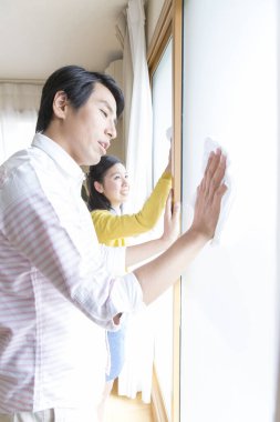 Beyaz elbiseli genç çift pencereyi temizliyor.