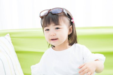 Kafasında gözlük olan mutlu Asyalı kızın portresi.