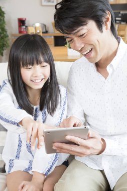 Evde tablet kullanan mutlu bir Asyalı aile.