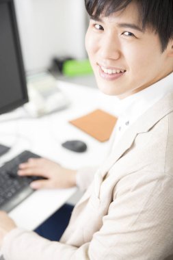 Bilgisayarda çalışan Asyalı genç adam.