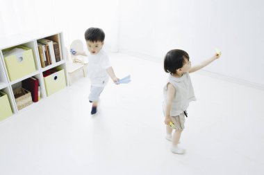 Asyalı çocuklar kağıt uçaklarla oynuyorlar.