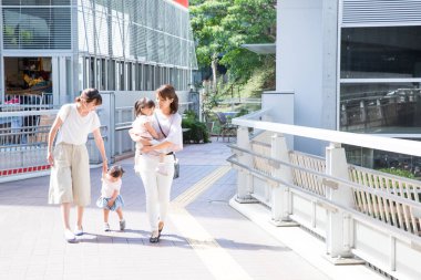 Güneşli bir günde çocuklarla yürüyen kadınlar