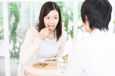 Asyalı kadın bir erkekle yemek yiyor. 